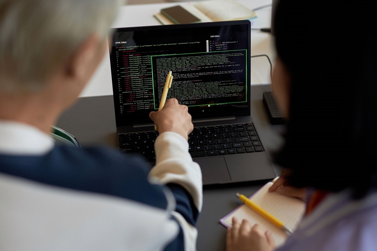 guy-with-pen-pointing-at-codes-on-laptop-screen-du-ESE25VA.jpg